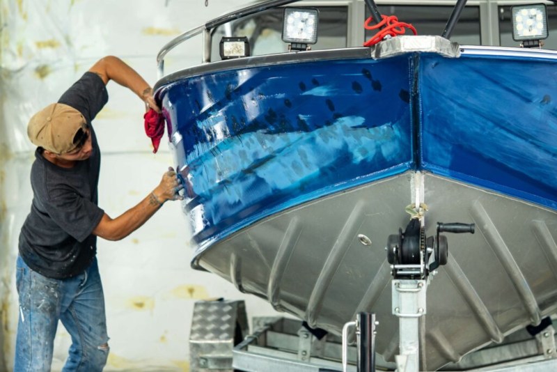 man repainting the side of a boat